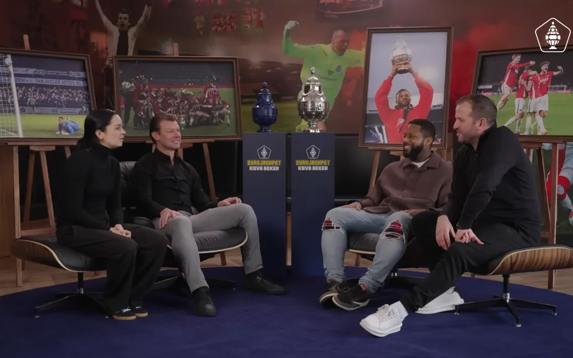 Alles of Niets met Jeremain Lens en Arthur Numan met trofeeën en sportfoto's op de achtergrond.