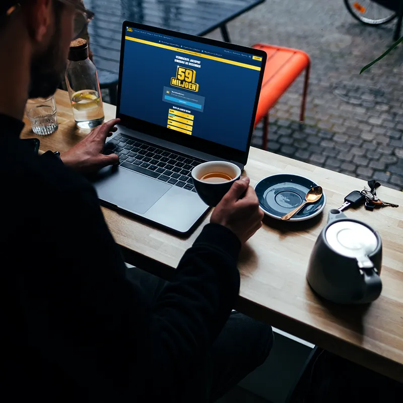 Persoon met een laptop die Eurojackpot speelt met een prijs van 59 miljoen.