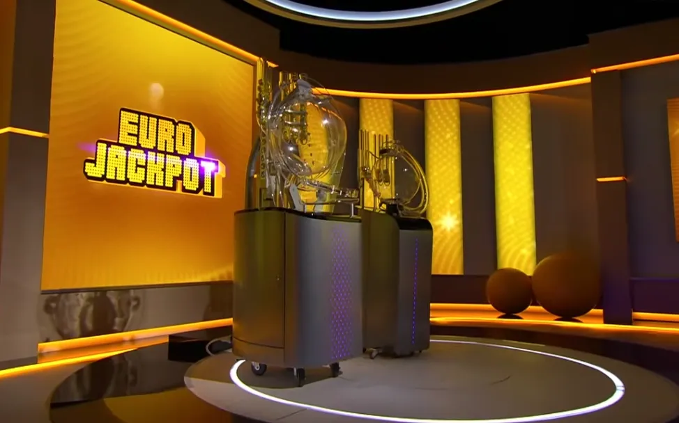 Studio-opstelling van Eurojackpot met loterijmachines en een gele achtergrond.